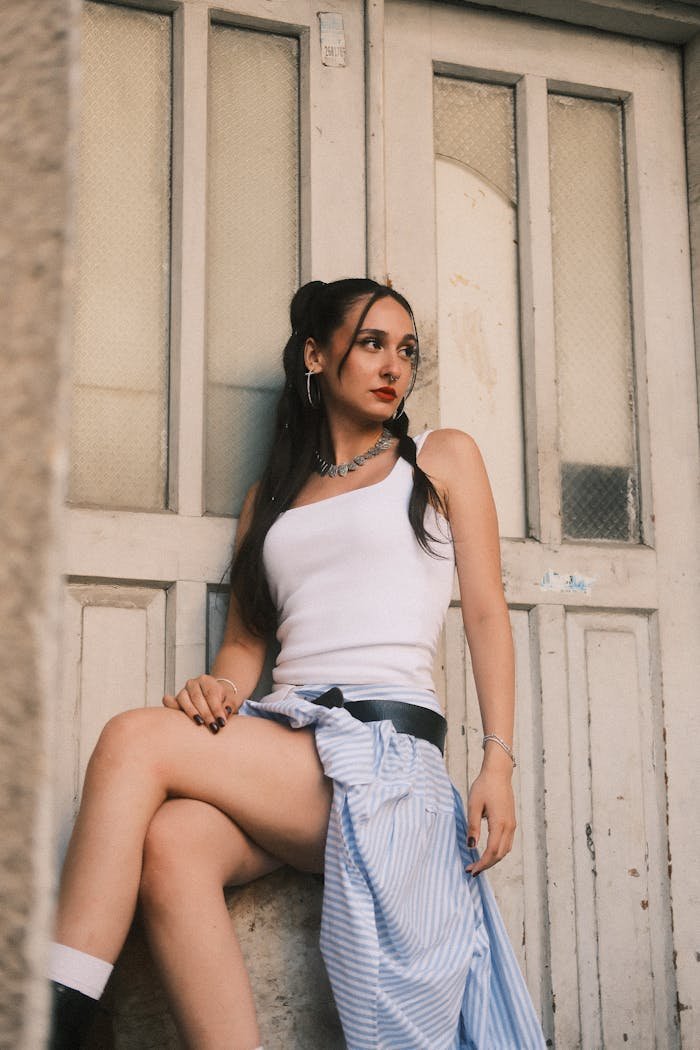 Home Trendy young woman in casual attire posing confidently by a vintage door.